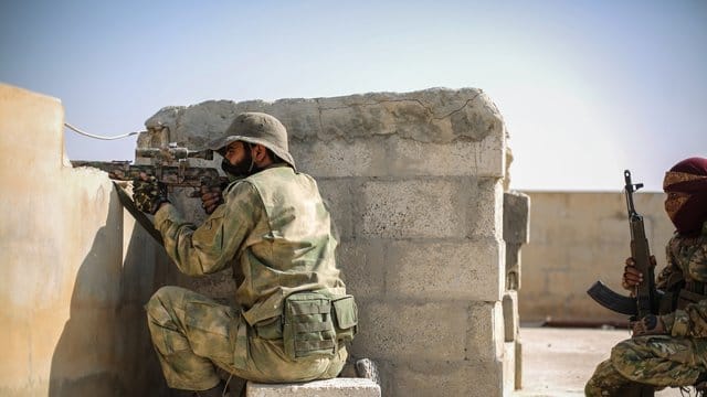 Ein Scharfschütze der mit der Türkei verbündeten Syrischen Nationalarmee zielt mit einer Waffe von einem Dach in Tall Abjad. Ein Scharfschütze der mit der Türkei verbündeten Syrischen Nationalarmee zielt mit einer Waffe von einem Dach in Tall Abjad.