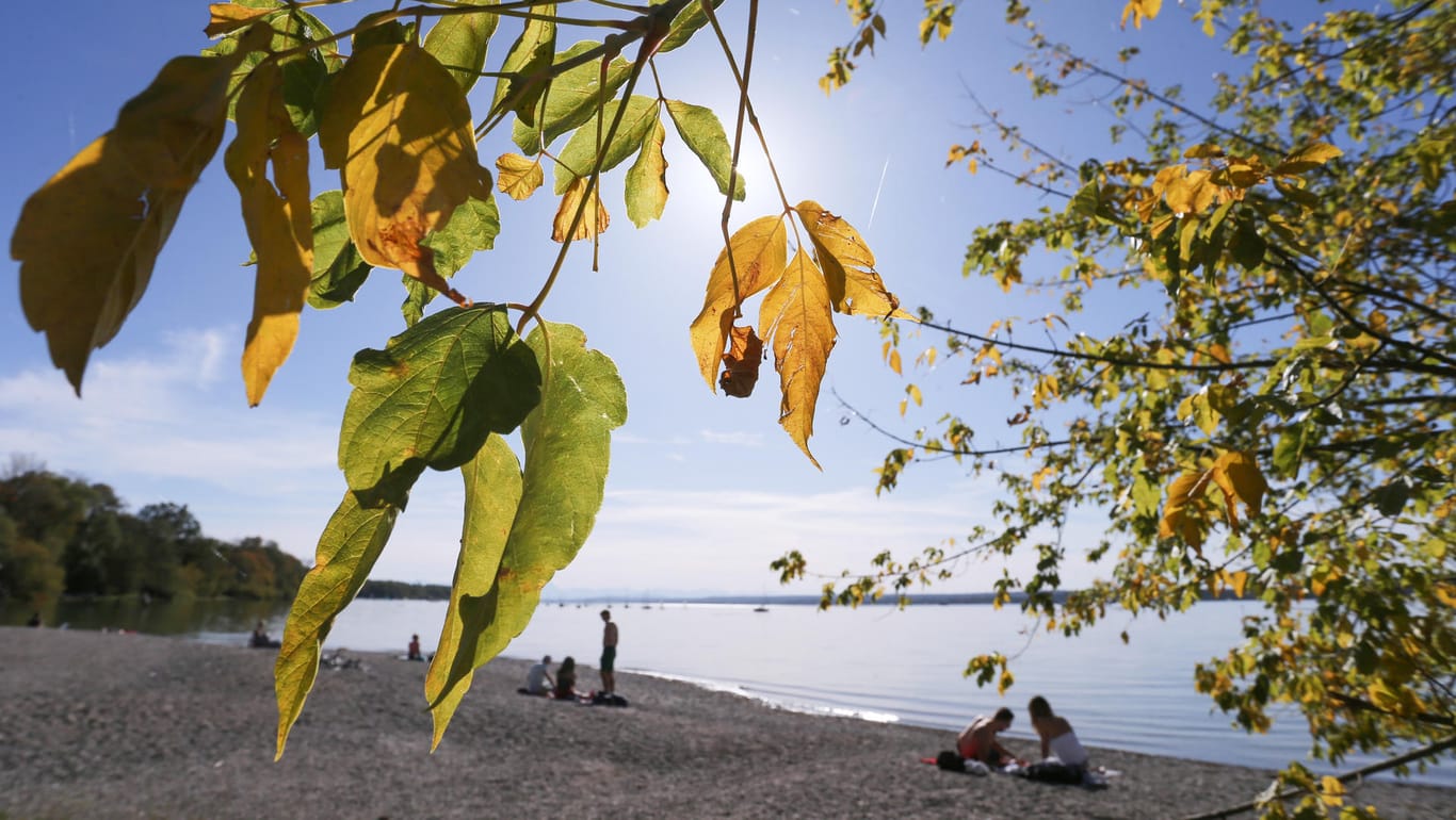 Goldener Oktober in Bayern: Ausflügler genießen am Ufer des Ammersees unter herbstlich gefärbten Bäumen den Sonnenschein.