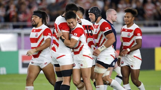 Die Spieler des japanischen Rugby-Teams feiern einen weiteren Versuch gegen Schottland. Die Spieler des japanischen Rugby-Teams feiern einen weiteren Versuch gegen Schottland.