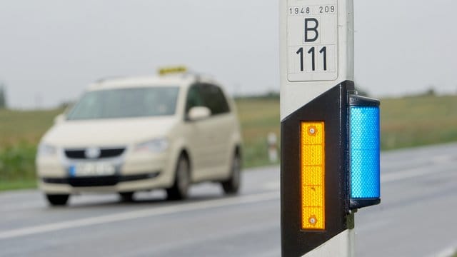 An diesem Leitpfosten ist ein blauer Wildwechselreflektor angebracht - die orangene Farbe des länglichen Streifens verweist auf eine Ausfahrt oder Einmündung.