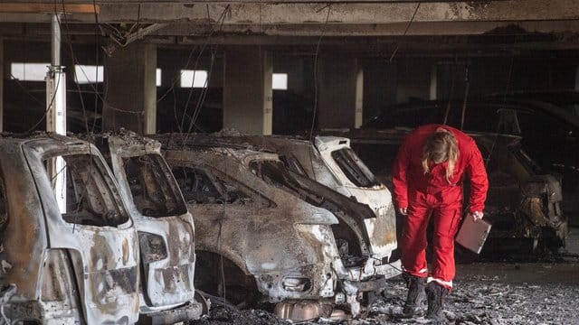 Ein Sachverständiger inspiziert in dem Parkhaus am völlig ausgebrannte Autos. Ein Sachverständiger inspiziert in dem Parkhaus am völlig ausgebrannte Autos.