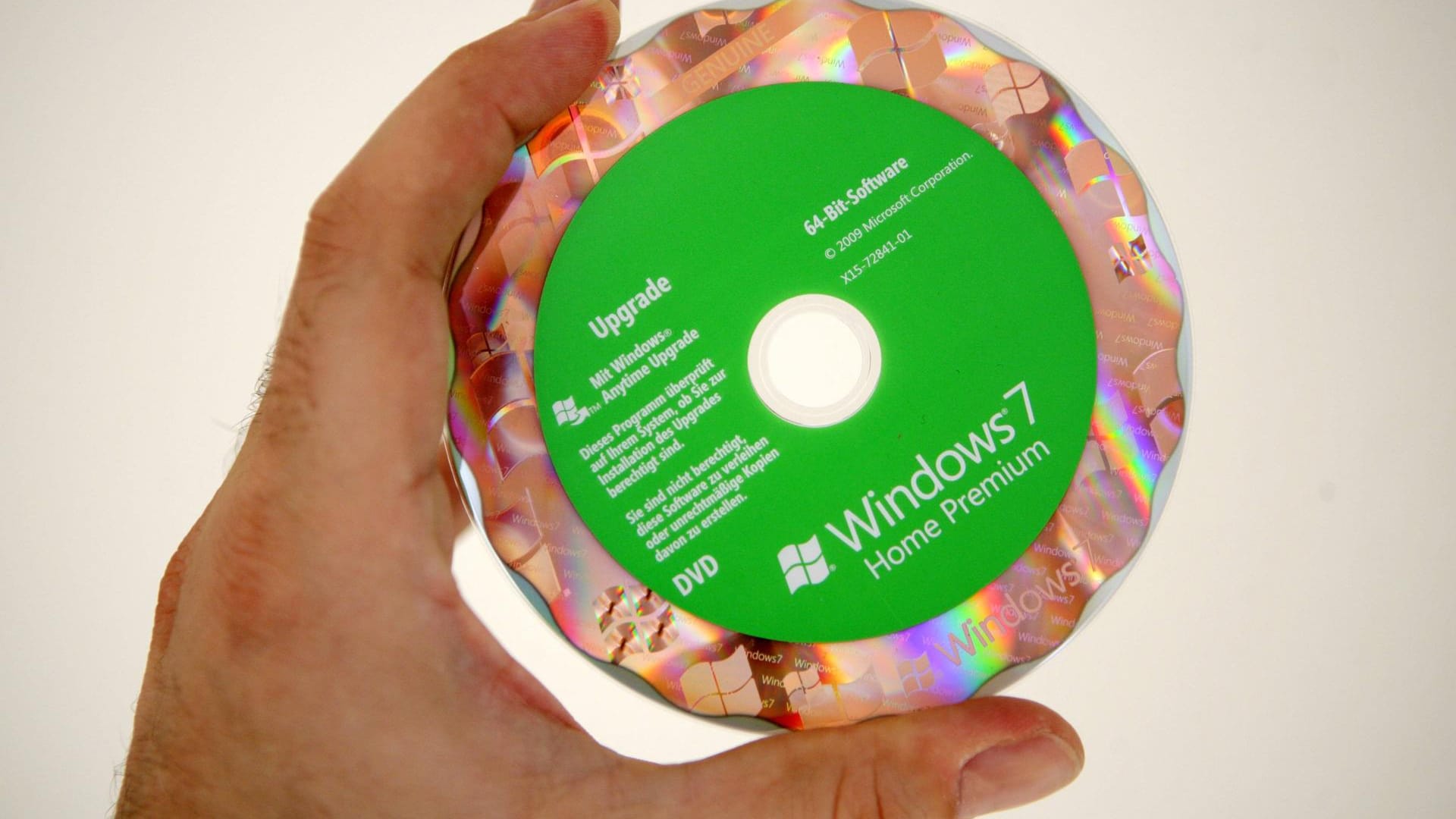 Eine Hand hält eine Installations-CD mit Windows 7: Das veraltete Betriebssystem wird im Januar in den Ruhestand geschickt.