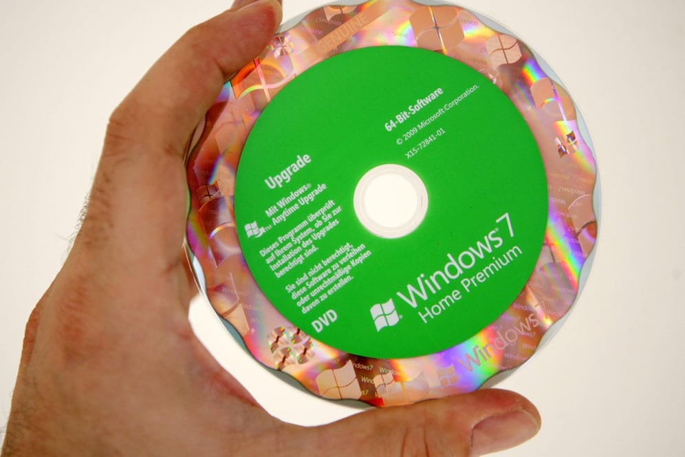 Eine Hand hält eine Installations-CD mit Windows 7: Das veraltete Betriebssystem wird im Januar in den Ruhestand geschickt.