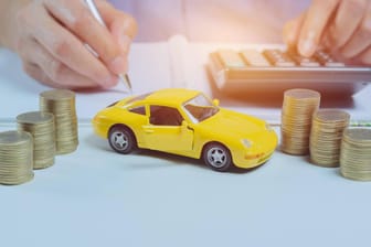 Taschenrechner und Modellauto: Wer jetzt seine Autoversicherung wechselt, könnte Geld sparen.