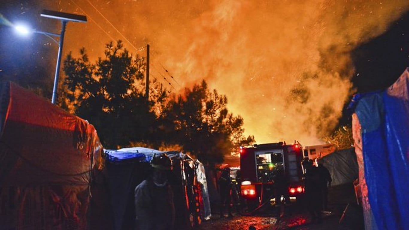 Feuerwehrleute kämpfen gegen den Brand in dem überfüllten Migrantenlager.