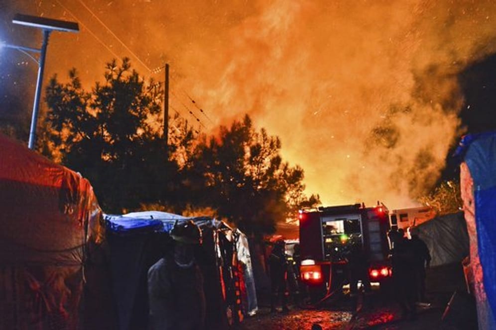 Feuerwehrleute kämpfen gegen den Brand in dem überfüllten Migrantenlager.