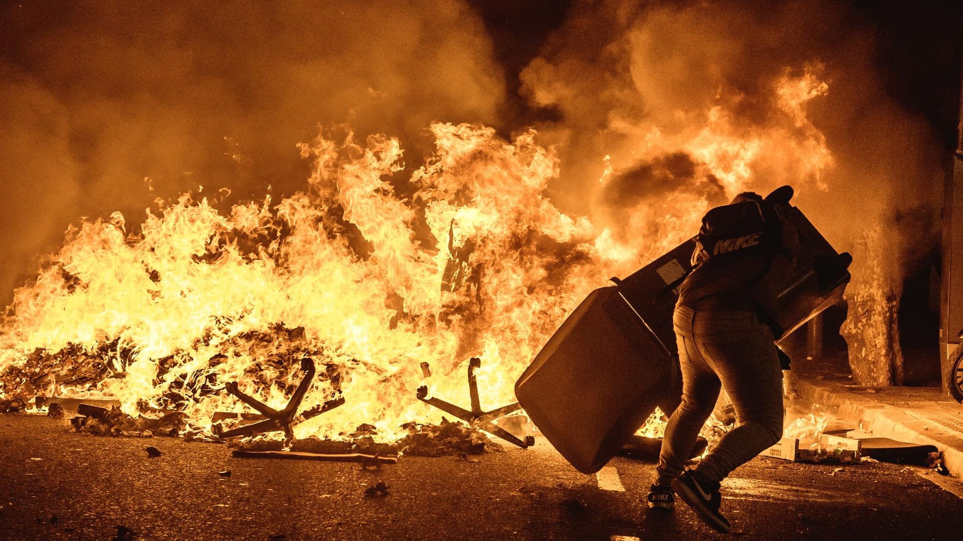 Barcelona am Dienstagabend: Ein Demonstrant wirft einen Mülleimer auf eine brennende Barrikade.