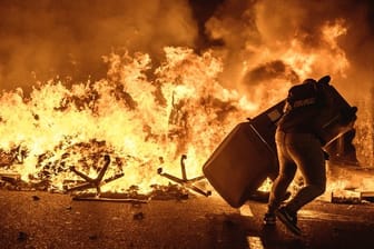 Ein Demonstrant wirft einen Mülleimer auf eine brennende Barrikade bei Protesten gegen die Verurteilung katalanischer Separatistenführer.