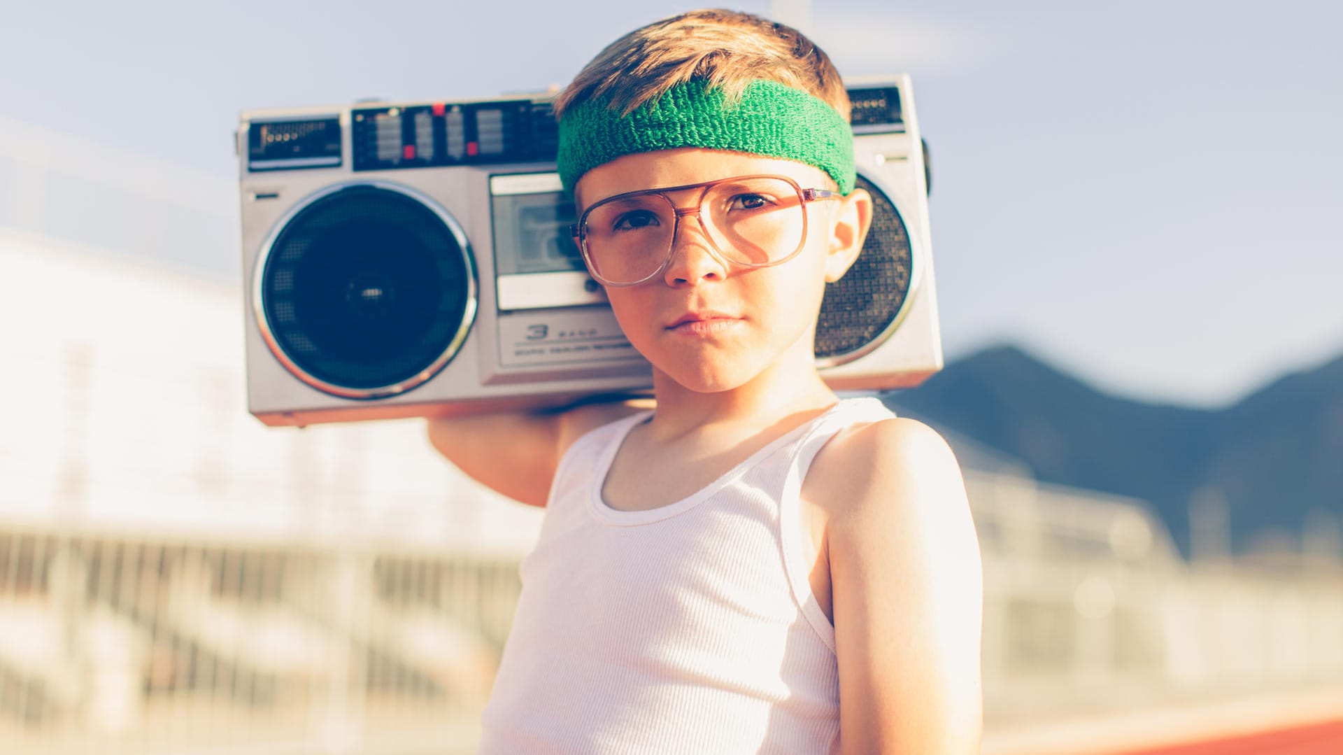 Junge mit Brille und Stirnband hört Radio