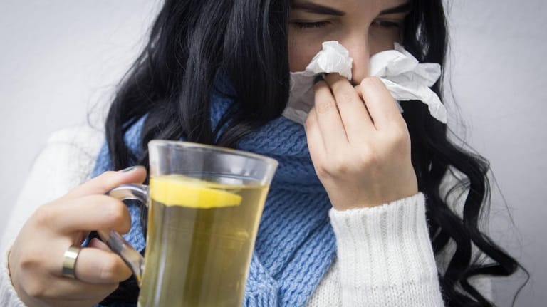 Eine erkältete Frau mit einer Tasse Tee: Warme oder heiße Getränke können Symptome durchaus lindern.