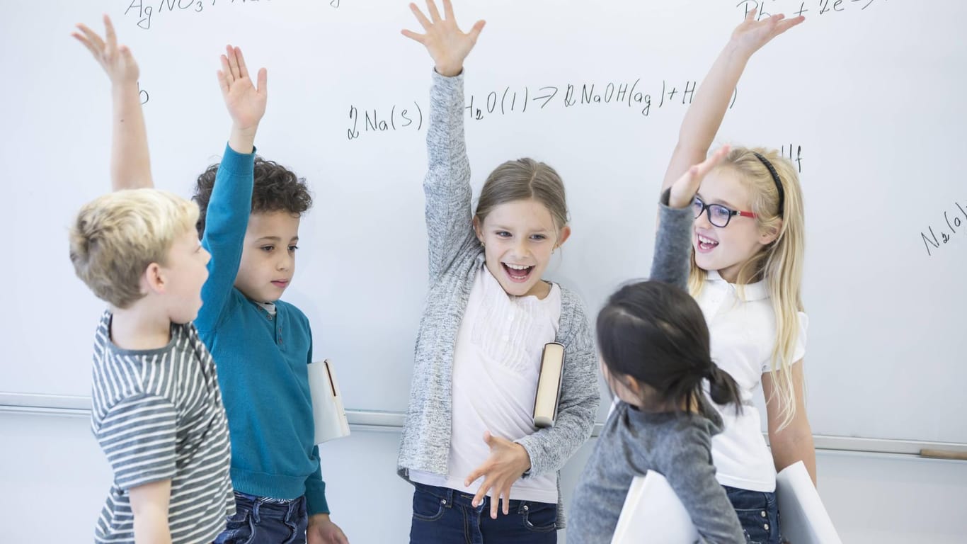 Kinder jubeln vor Tafel: Schlaue Eltern, schlaues Kind? Wissenschaftler gehen davon aus, dass Intelligenz zu Teilen vererbt wird.