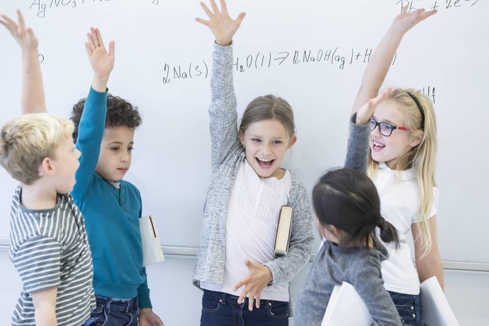 Kinder jubeln vor Tafel: Schlaue Eltern, schlaues Kind? Wissenschaftler gehen davon aus, dass Intelligenz zu Teilen vererbt wird.