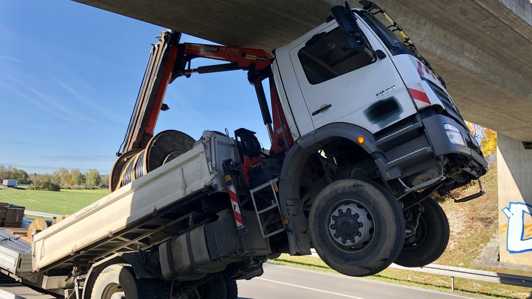 Der LKW in Bichl in Oberbayern: Mit seinem nicht eingefahrenen Ladekran riss der 80-jährige Fahrer erst die Oberleitung der Bahn ab und blieb dann an einer Brücke hängen.