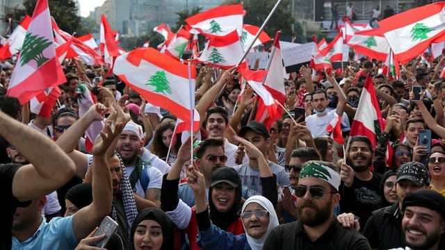 Demonstranten schwenken libanesische Flaggen und fordern wegen der schweren Wirtschaftskrise im Land einen Regierungswechsel. Demonstranten schwenken libanesische Flaggen und fordern wegen der schweren Wirtschaftskrise im Land einen Regierungswechsel.