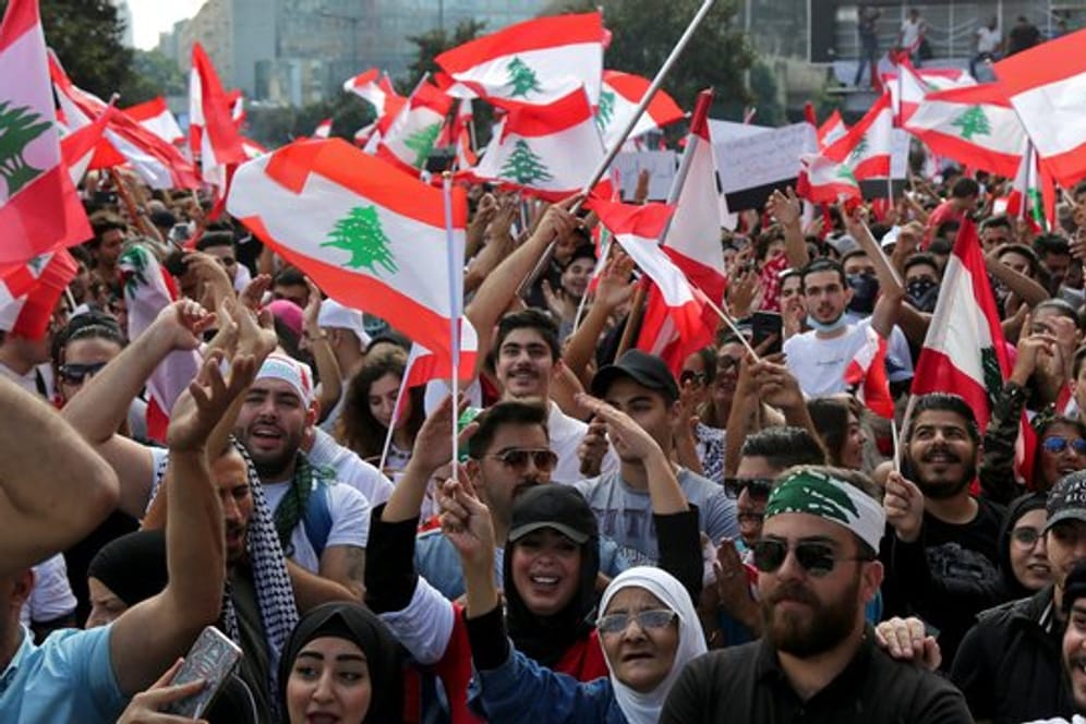 Demonstranten schwenken libanesische Flaggen und fordern wegen der schweren Wirtschaftskrise im Land einen Regierungswechsel.
