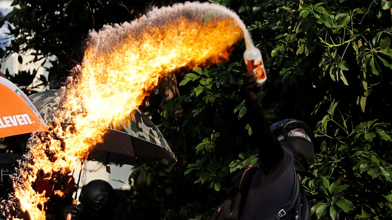 Demonstrant schleudert eine Benzinbombe: Die Polizei hält mit Wasserwerfern und Tränengas dagegen.