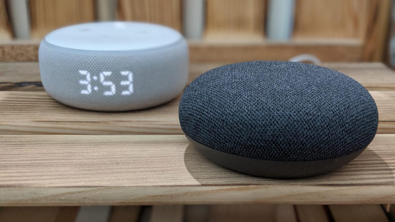 Ein Amazon Echo Dot und ein Google Nest Mini auf einem Bücherregal: Beide Smart Speaker sind günstig, aber welcher ist besser?