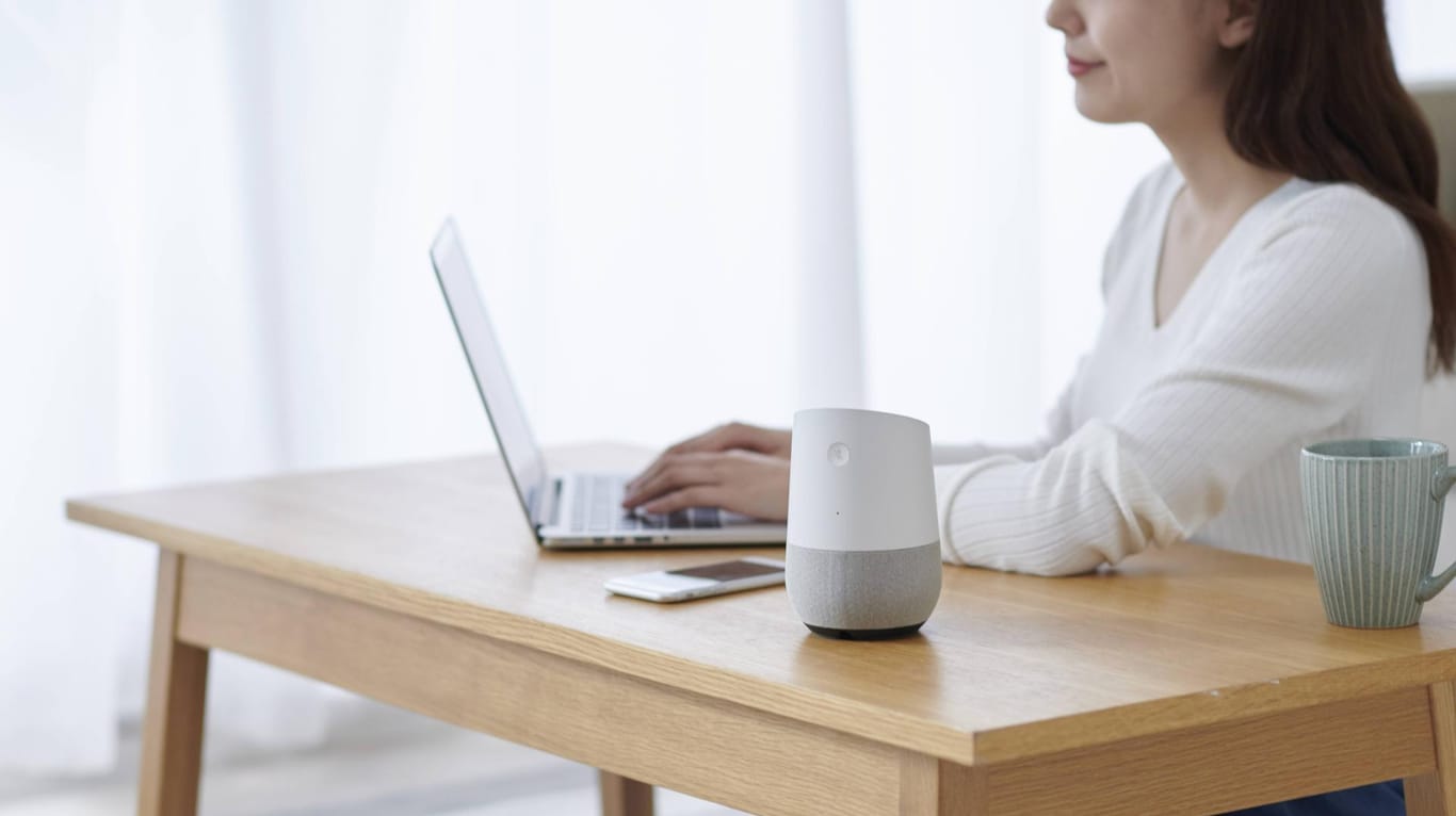 Eine Frau arbeitet an einem Tisch, auf dem ein Smart Speaker steht: Die vernetzten Lautsprecher lassen sich in Wanzen verwandeln.