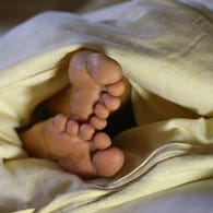 Füße gucken unter der Bettdecke hervor: Wie sehr stört die Zeitumstellung wirklich unseren Schlafrhythmus?