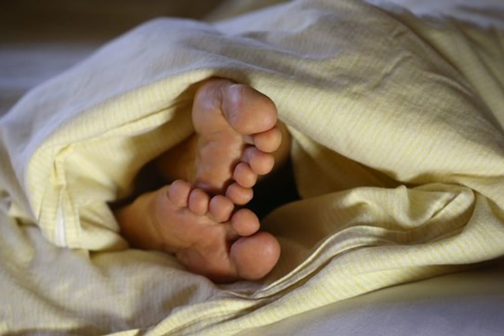 Füße gucken unter der Bettdecke hervor: Wie sehr stört die Zeitumstellung wirklich unseren Schlafrhythmus?