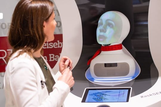 Eine Frau spricht im Reisenzetrum des Hauptbahnhofs mit "Semmi", einem Roboter vom Kundenservice der Deutsche Bahn, der auf Basis Künstlicher Intelligenz (KI) funktioniert.