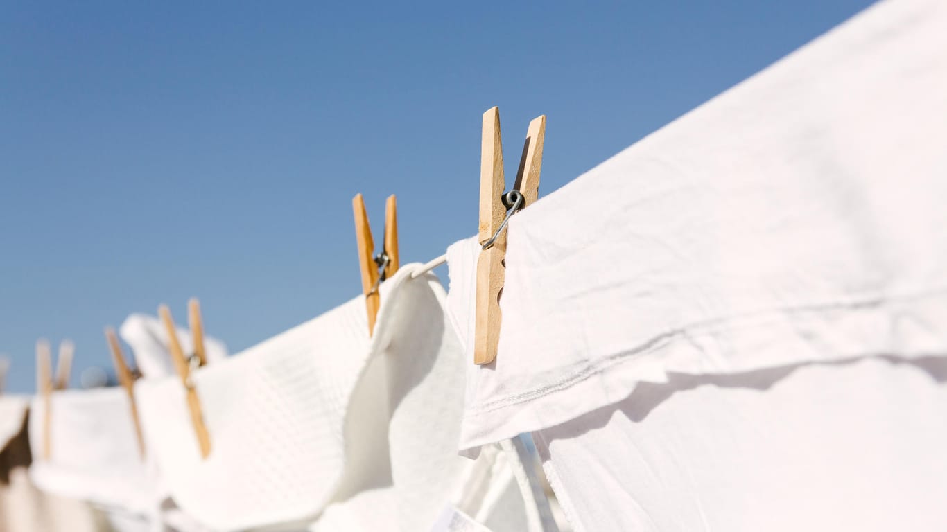 Weiße Wäsche hängt auf der Leine: Wer die Waschtemperatur von 40 und 60 Grad einhält, kann Küchen- und Handtücher zusammen waschen.