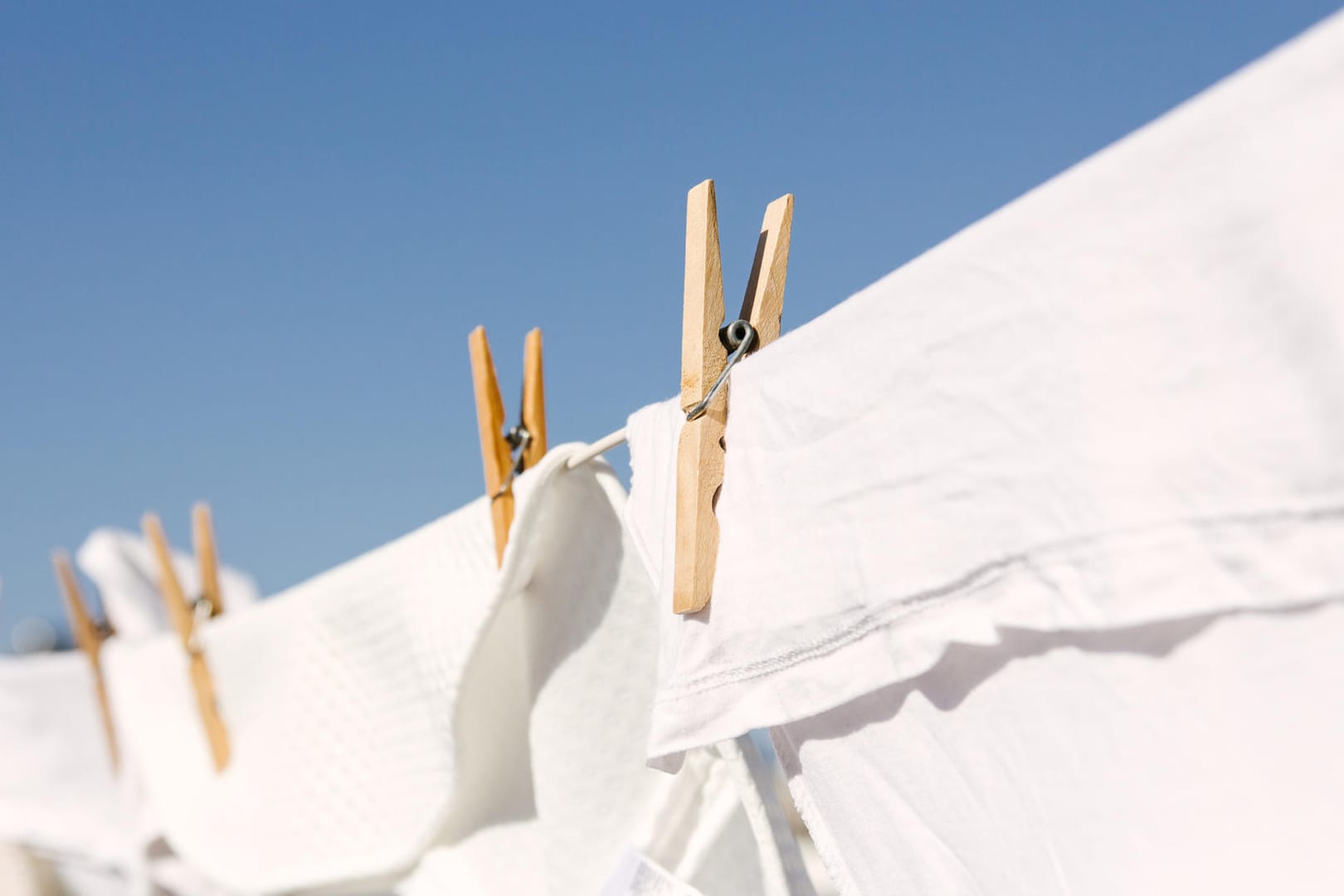 Weiße Wäsche hängt auf der Leine: Wer die Waschtemperatur von 40 und 60 Grad einhält, kann Küchen- und Handtücher zusammen waschen.