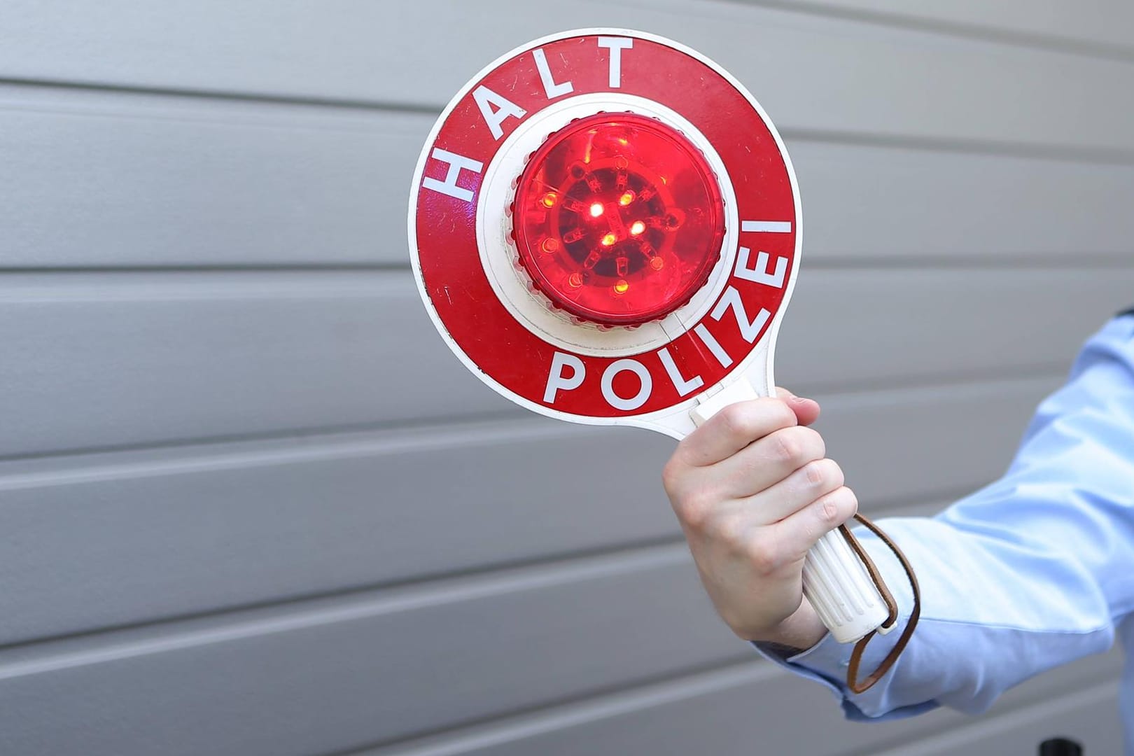 Ein Polizist mit einer Kelle: Nachdem die Beamten den Mann bei dem Schilderwechsel beobachtet hatten, kontrollierten sie sein Fahrzeug. (Symbolbild)