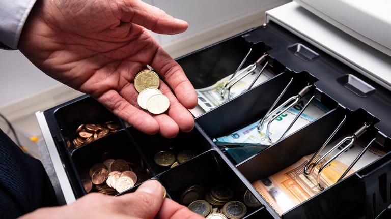 Eine Hand mit Bargeld: Münzen und Scheine sind ähnlich keimbelastet wie die Türgriffe öffentlicher Toiletten.