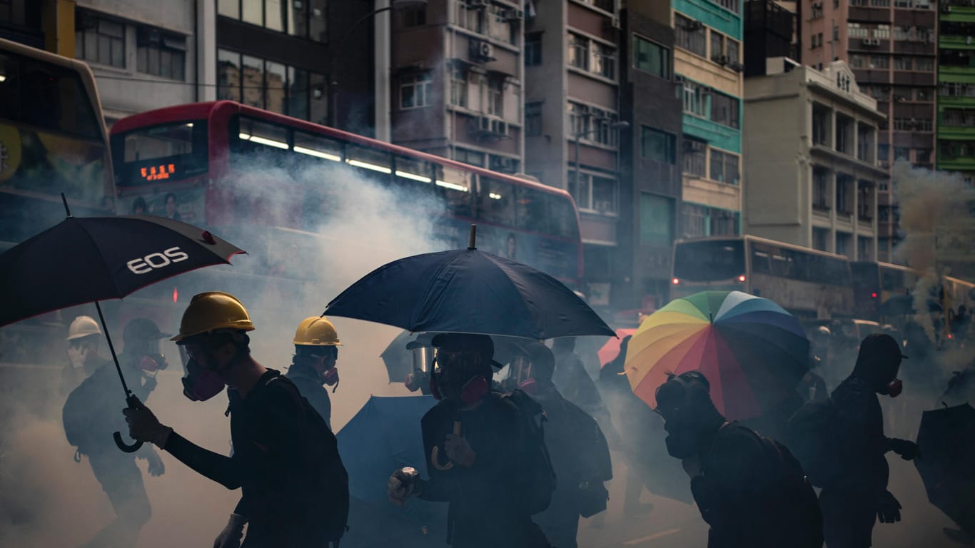 Demonstranten schützen sich mit Regenschirmen und Atemschutzmasken gegen das Tränengas der Polizei: Die Regierung geht hart gegen die Proteste vor.