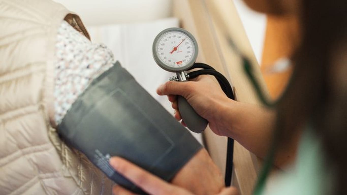 Eine Pflegerin misst bei einer Seniorin den Blutdruck.