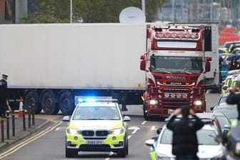 Ein Polizeiauto eskortiert den Lkw, in dem 39 Leichen gefunden worden waren, beim Verlassen des Waterglade Industrieparks.