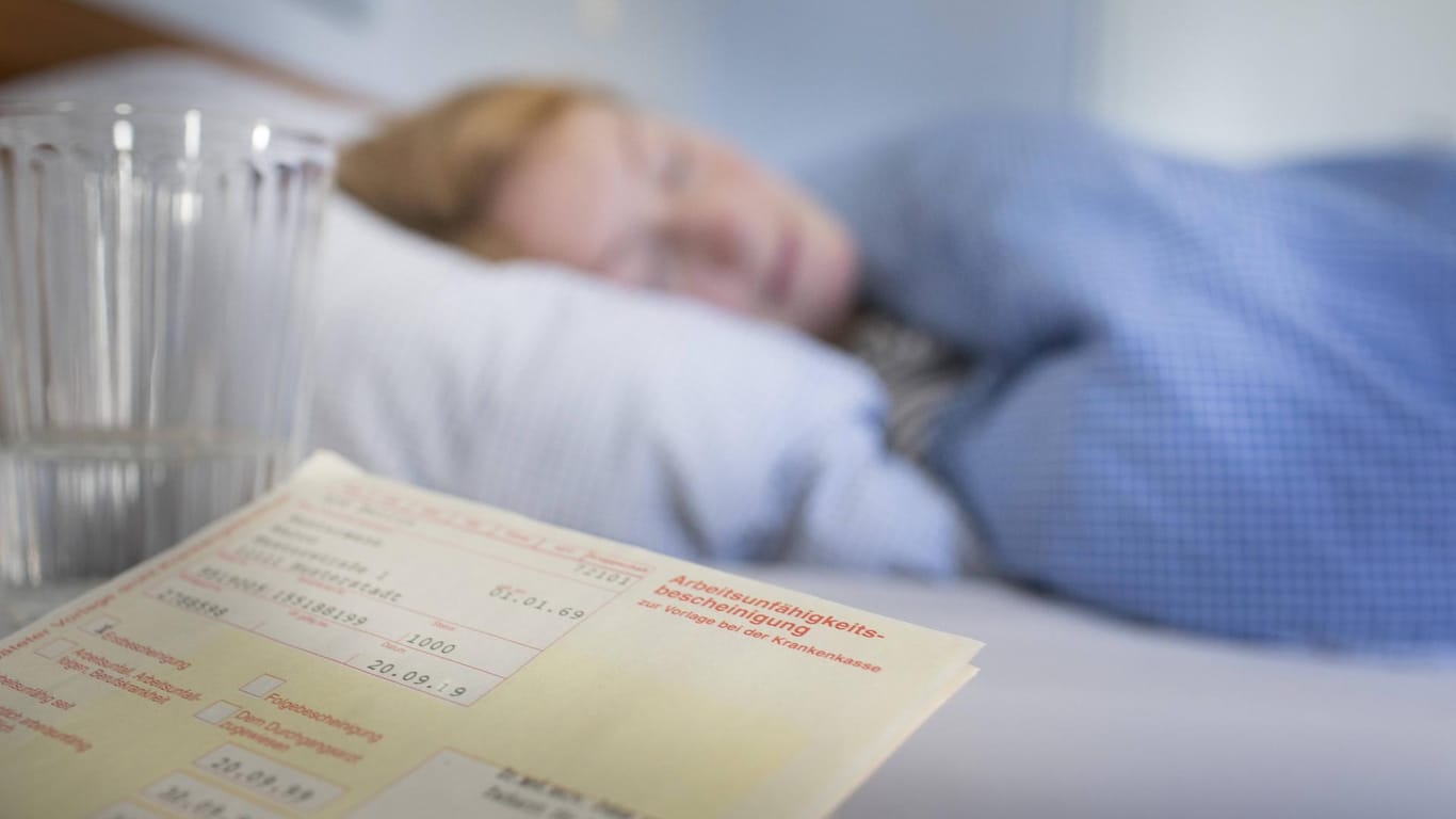 Eine Frau liegt im Bett neben einem Krankenschein: Weil immer mehr Menschen wegen psychischer Leiden erkranken, wird eine Anti-Stress-Verordnung gefordert.