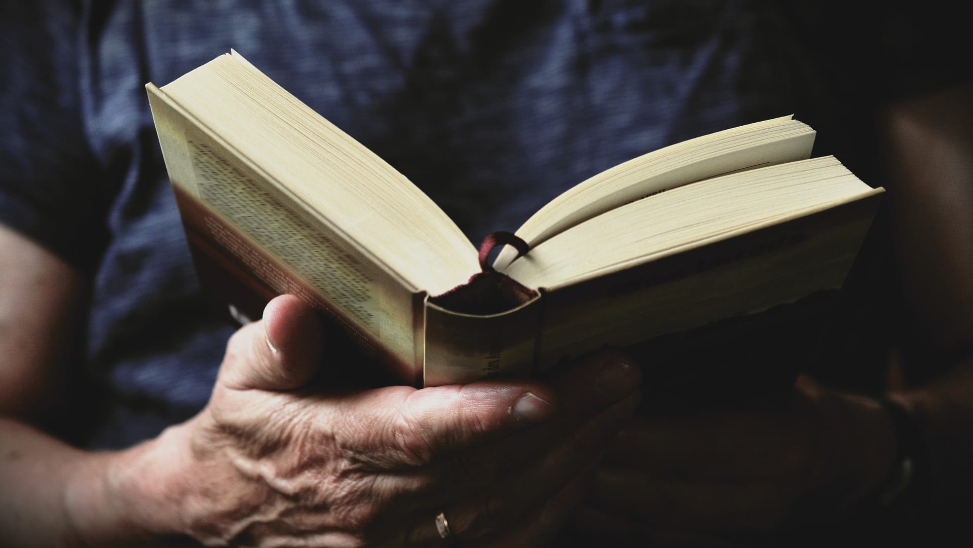 Ein Mann hält ein aufgeschlagenes Buch in der Hand. Wir suchen Ihr Lieblingsbuch: Machen Sie mit!