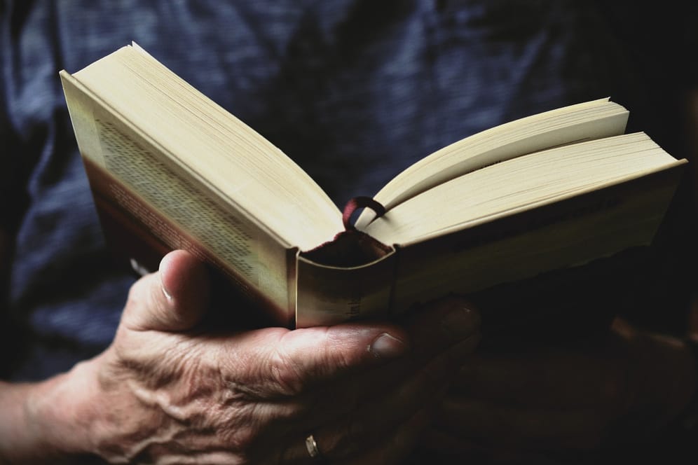 Ein Mann hält ein aufgeschlagenes Buch in der Hand. Wir suchen Ihr Lieblingsbuch: Machen Sie mit!
