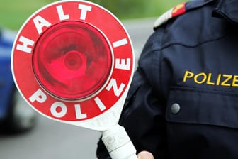 Ein Polizist hält eine Kelle: In Mainz riefen mehrere Zeugen die Polizei, weil sie einen verdächtigen Autofahrer bemerkten.