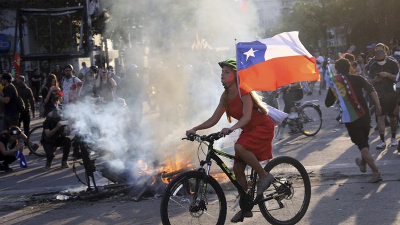 Bei einer Protestaktion gegen die Regierung hat eine junge Frau in Santiago ihr Fahrrad mit der chilenischen Flagge ausgestattet.