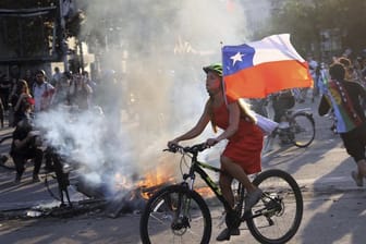 Bei einer Protestaktion gegen die Regierung hat eine junge Frau in Santiago ihr Fahrrad mit der chilenischen Flagge ausgestattet.