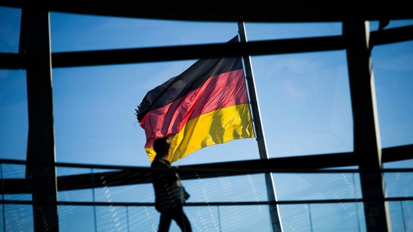 Vor der Kuppel des Reichstaggebäudes weht die Deutschlandfahne.