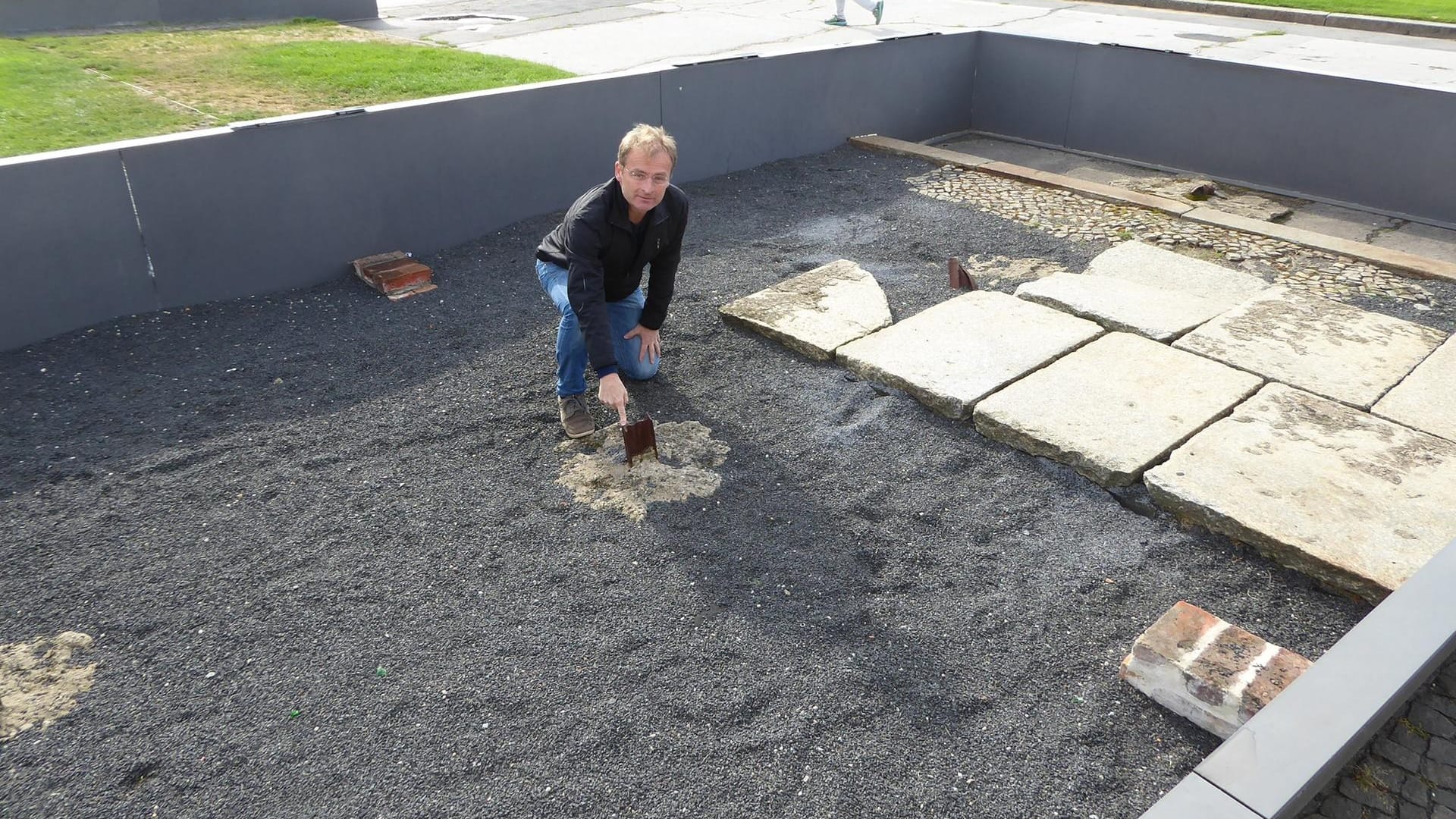 Torsten Dressler: Der Gegenwartsarchäologe kniet auf dem Gelände der Gedenkstätte Berliner Mauer in einem sogenannten archäologischen Fenster.