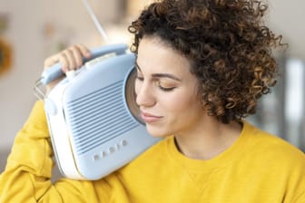 Woman listening to music with portable radio at home model released Symbolfoto property released PUB