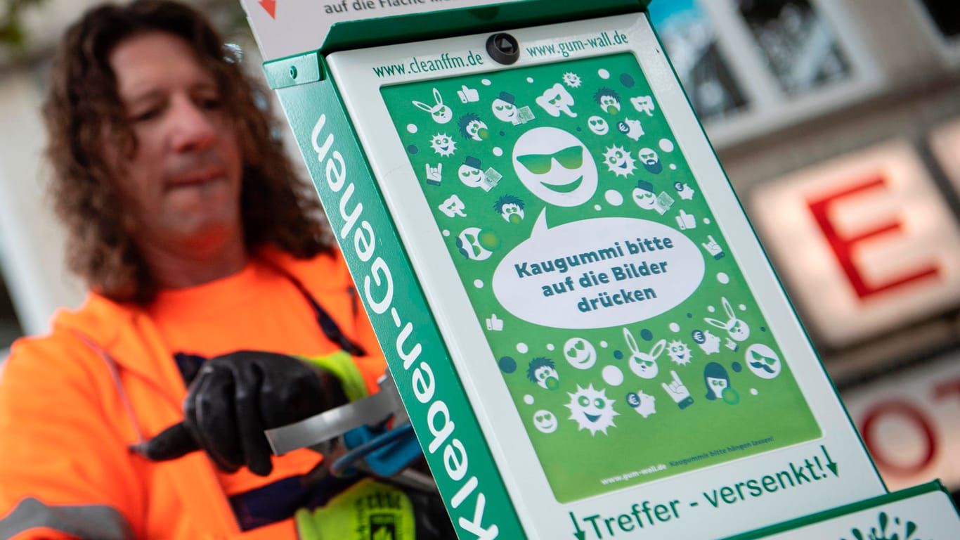 Ein Mitarbeiter der Stadtreinigung montiert eine "Gum-Wall": Die Stadt Frankfurt will gegen Kaugummi-Dreck auf der Straße vorgehen.