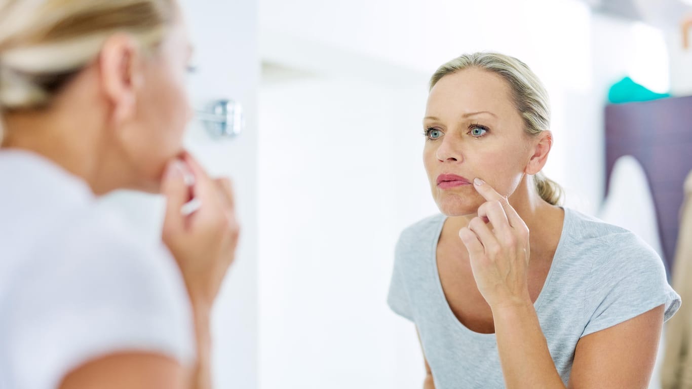 Eine Frau betrachtet sich im Spiegel: Tretinoin soll Falten glätten und die Hautstruktur verbessern.