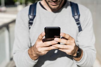 Ein Mann nutzt ein Smartphone: In Mainz ist ein 26-Jähriger in eine Betrugsfalle via App getappt.