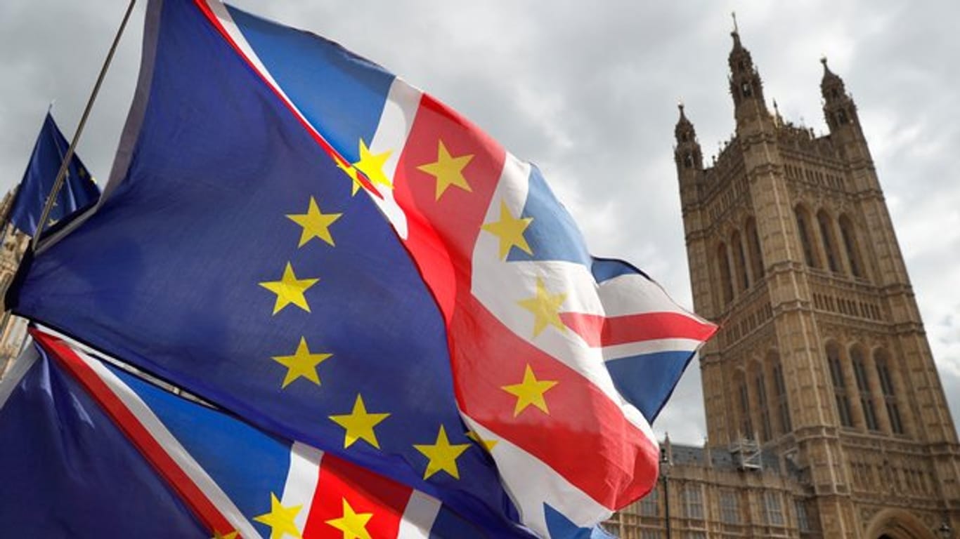 Fahnen, die jeweils zur Hälfte aus dem britischen Union Jack und der Flagge der Europäischen Union bestehen, vor dem Palace of Westminster.