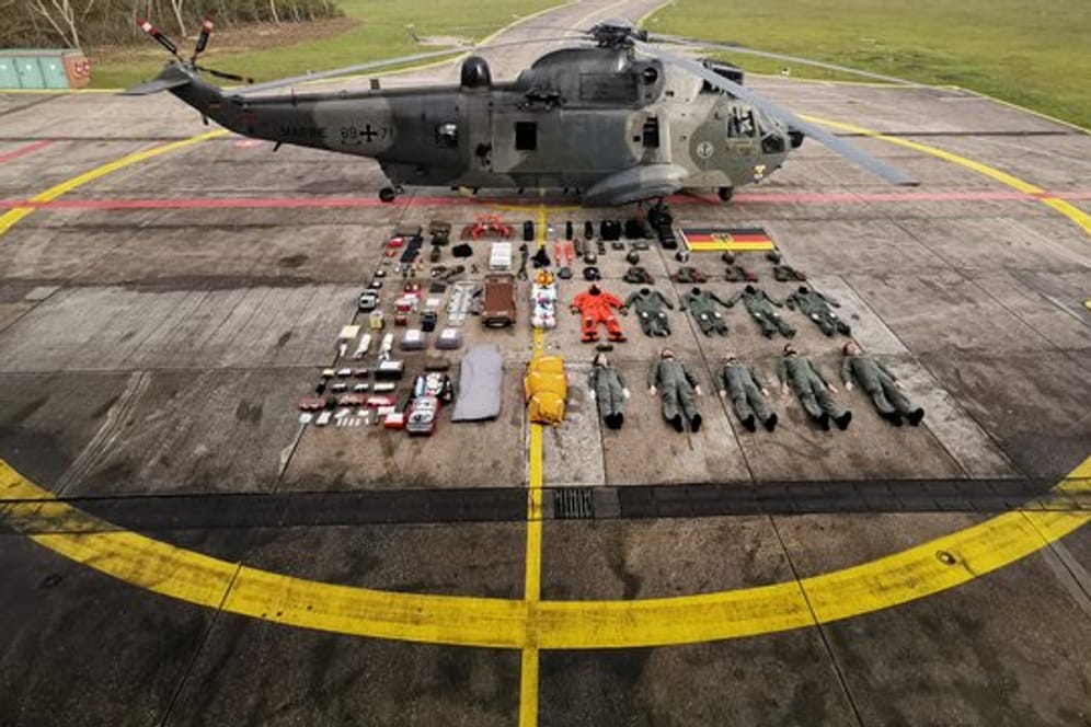 Fünf Seenotretter samt Ausrüstung liegen neben dem Rettungshelikopter SeaKing MK41.