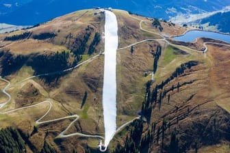 In den Kitzbüheler Alpen ist konservierter Schnee aus dem vergangenen Winter zu einer Piste zusammengeschoben worden.