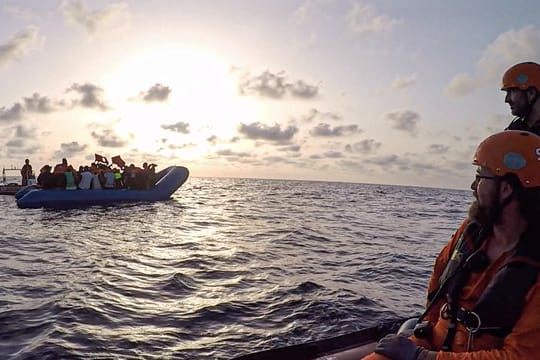 Seenotretter vom Rettungsschiff "Alan Kurdi" blicken zu einem Schlauchboot voller Flüchtlinge (Archiv).