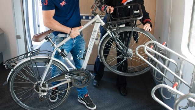 Ein Fahrgast verstaut sein Fahrrad in einem ICE 4, während ihm eine Zugführerin dabei hilft. Ein Fahrgast verstaut sein Fahrrad in einem ICE 4, während ihm eine Zugführerin dabei hilft.
