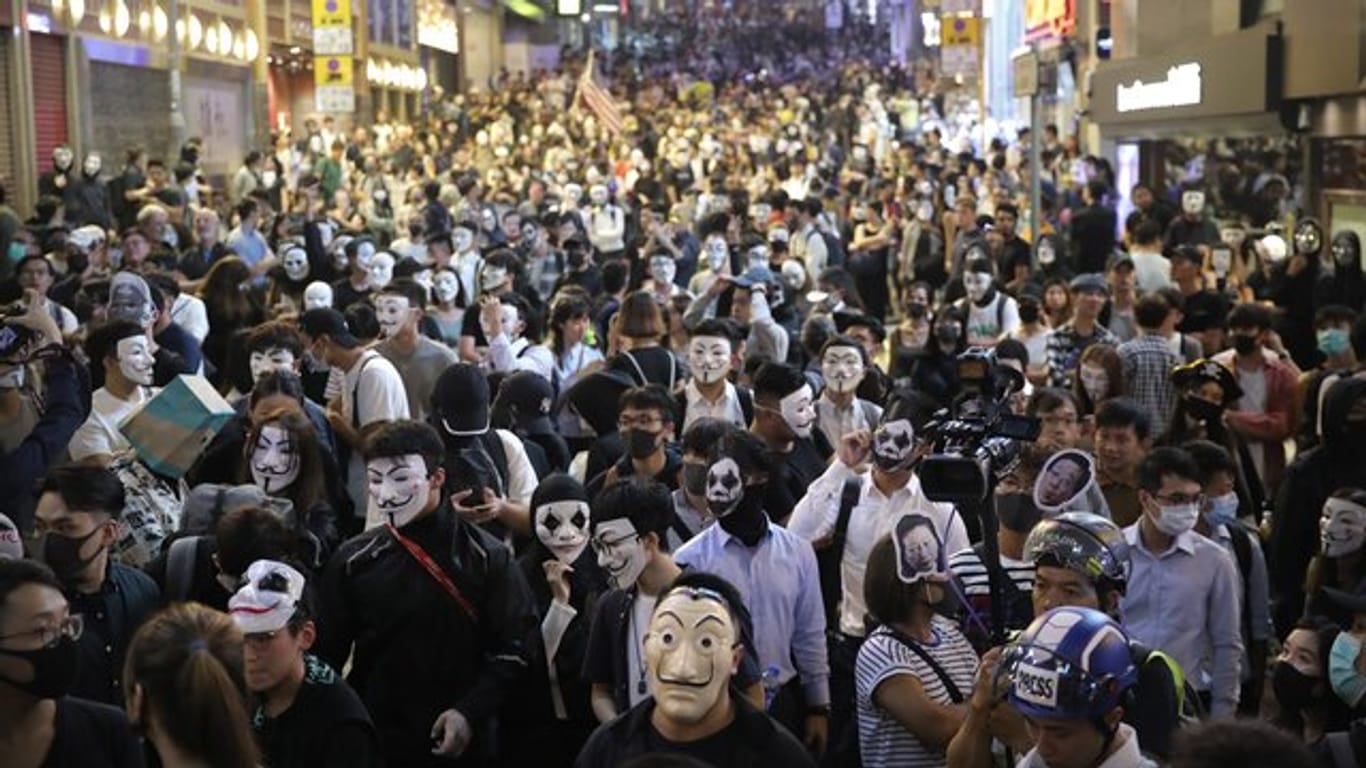 Maskierte Demonstranten versammeln sich auf einer Straße in Hongkong.